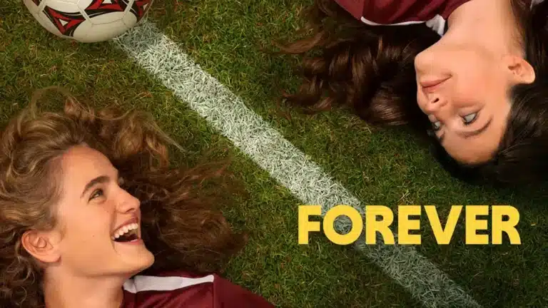 Escena de la película Forever con dos jóvenes sonrientes recostados en un campo de fútbol